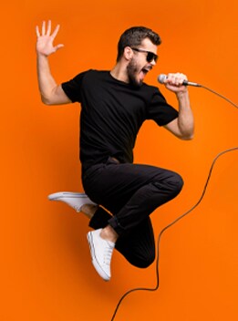 Modelo masculino con playera negra de manga corta, pantalón negro, tenis blancos y lentes negros para el sol.
