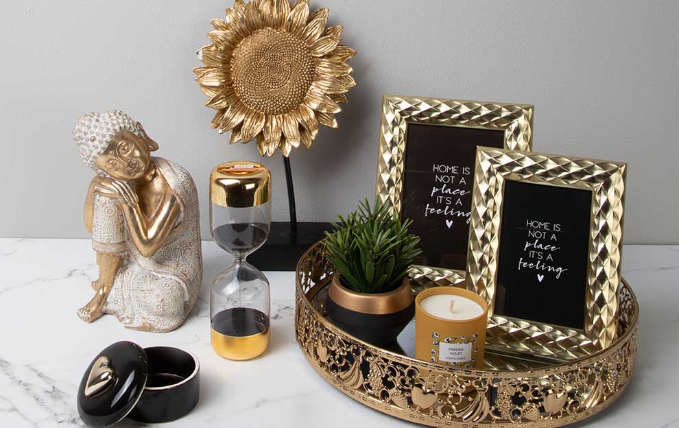 Accesorios de diseño para interiores en colores dorados. Marcos para fotografías, copas, figuras, velas y macetas de cerámica.