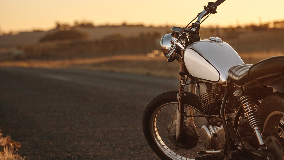 Motocicleta tipo vintage sobre la carretera al atardecer
