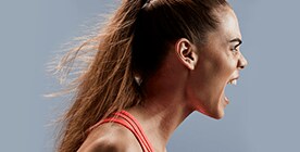 Detalle de rostro de mujer joven, de lado, que grita con energía.